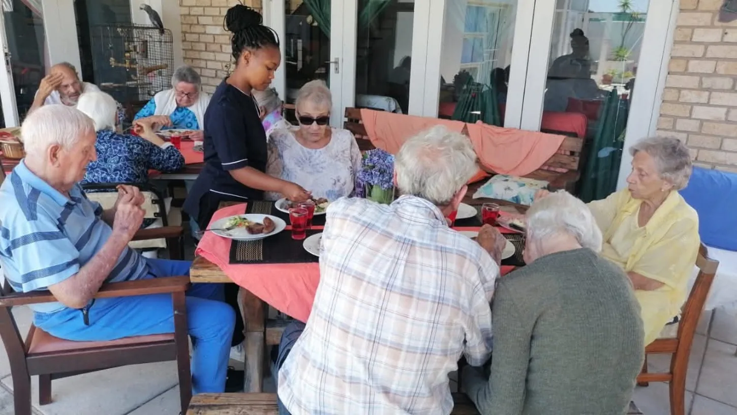 Residents enjoying a shared meal with a caregiver